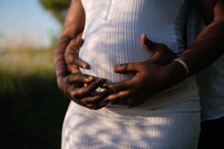 a couple holding hands over the woman’s pregnant belly