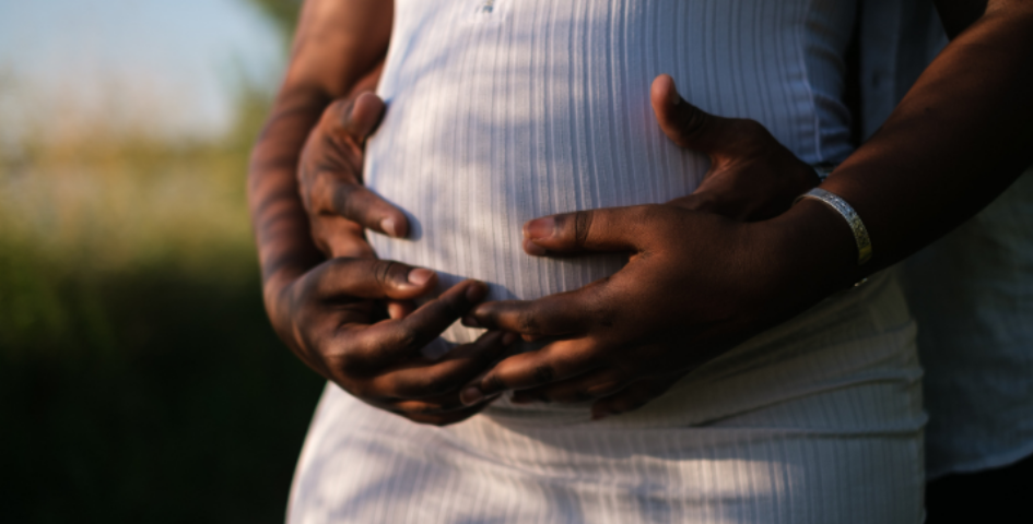 a couple holding hands over the woman’s pregnant belly