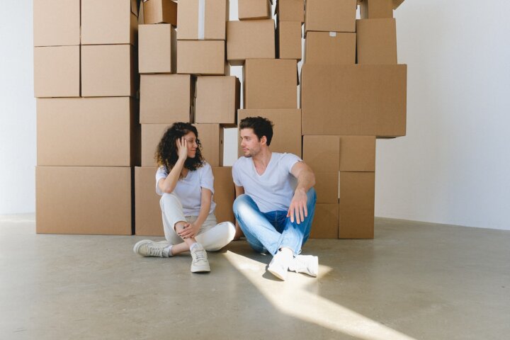 a couple on the floor with boxes behind them discussing how location can influence your fertility journey