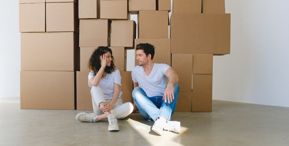 a couple on the floor with boxes behind them discussing how location can influence your fertility journey