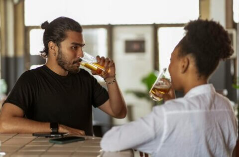Man in a black shirt and woman drinking beer.