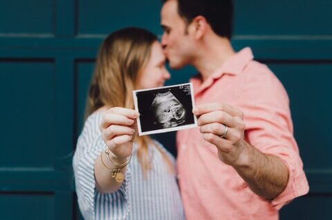 Couple kissing and holding a photo of an ultrasound