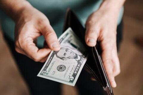 A man taking a five-dollar bill out of his wallet